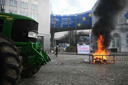 Un incendio y un tractor se ven frente al Parlamento Europeo, en la Plaza de Luxemburgo, durante una protesta de agricultores para denunciar las reformas de la Política Agrícola Común (PAC) y acuerdos comerciales como el Mercosur, en Bruselas, el 18 de diciembre de 2025