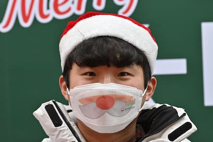 Un joven con una máscara facial navideña en Seúl el 23 de diciembre de 2020, cuando Corea del Sur prohibió las reuniones de más de cuatro personas en la capital y áreas circundantes en medio de un aumento en los casos del coronavirus