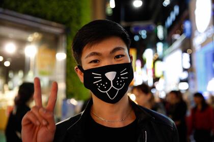 Un joven coreano posa divertido para la foto con su media careta de gato en Seúl.