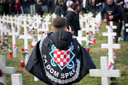Un joven envuelto en insignias de derechas fotografía el cementerio en el aniversario de la caída de la ciudad de Vukovar, Croacia, durante la guerra de 1991-1995, ante el Ejército yugoslavo liderado por serbios, el 18 de noviembre de 2025. (Foto AP/Darko Bandic)