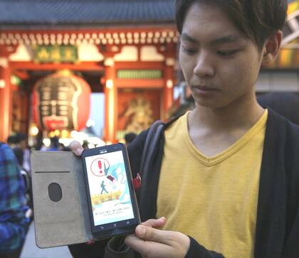 Un joven japonés muestra el juego en la pantalla de su celular