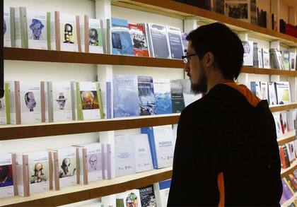 Un joven lector, atento a los títulos de La Serie de los Dos Siglos, colección de literatura argentina de Eudeba