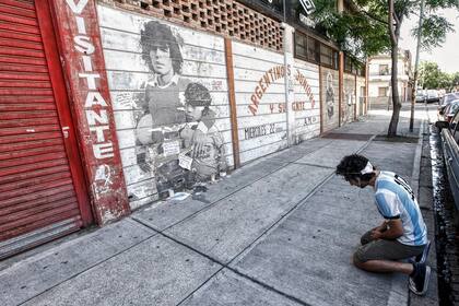 Un joven llora frente a un mural pintado en la cancha de Argentinos juniors