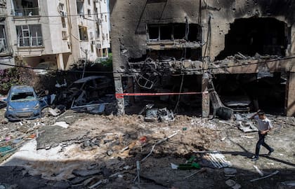 Un joven pasa frente a un edificio destruido por un cohete disparado desde Gaza en Petah Tikva, un suburbio de Tel Aviv, Israel, el 13 de mayo de 2021
