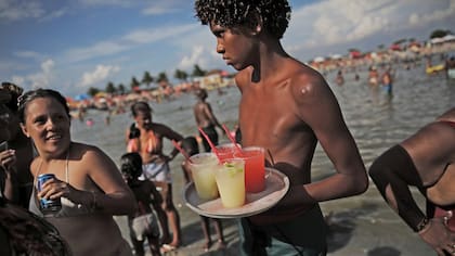 Un joven reparte caipirinhas, en el estanque artificial conocido como piscinao, o piscina grande, al norte de Río de Janeiro en Brasil.