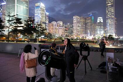 Un joven utiliza un telescopio para ver el fenómeno en Victoria Harbour, Hong Kong 