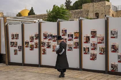 Un judío ultraortodoxo camina junto a un muro con fotografías de rehenes. en su mayoría civiles israelíes que fueron secuestrados durante el ataque sin precedentes de Hamás a Israel el 7 de octubre.