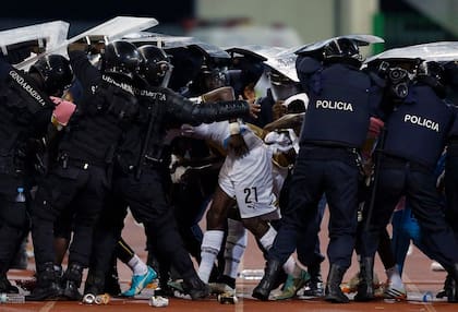 Un jugador de Ghana es protegido por fuerzas de seguridad locales
