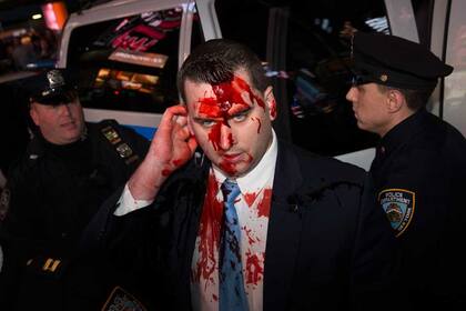 Un líquido que imita sangre corre por la cara de un agente de policía en Nueva York
