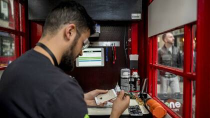 Un local de arreglo de celulares en una vieja cabina telefónica
