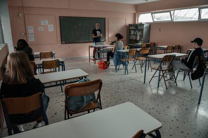 Un maestro habla con los estudiantes de último año en un aula de una escuela secundaria en Atenas el 11 de mayo de 2020 cuando Grecia reabrió las escuelas después de 2 meses desde su cierre debido a la pandemia de coronavirus
