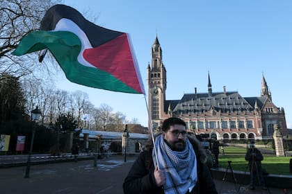 Un manifestante alza una bandera palestina frente al Palacio de la Paz, sede de la Corte Internacional de Justicia, en La Haya, Holanda, viernes 26 de abril de 2024