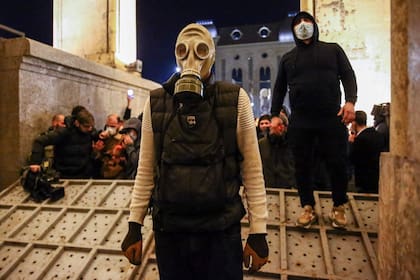 Un manifestante con una máscara antigás sobre una barrera derribada durante una manifestación frente al Parlamento georgiano, en Tiflis, el 7 de marzo de 2023.