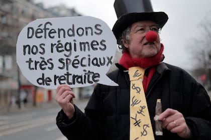 Un manifestante disfrazado que sostiene un cartel que dice "Defendamos nuestros regímenes de pensiones muy especiales" posa ante una manifestación, el jueves 19 de enero de 2023 en París