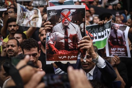 Un manifestante egipcio sostiene un cartel con una imagen del primer ministro israelí, Benjamin Netanyahu, y un texto en árabe que dice "Criminal de guerra".