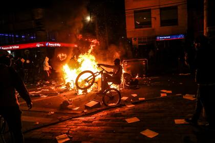 Un manifestante en una bicicleta en una barricada durante los enfrentamientos con la policía que estallaron durante una protesta contra la muerte de un abogado bajo custodia policial, en Bogotá