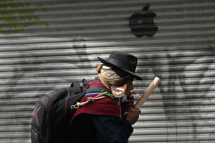 Un manifestante enciende una bengala con un cigarrillo durante una protesta que exige la renuncia del presidente boliviano Rodrigo Paz