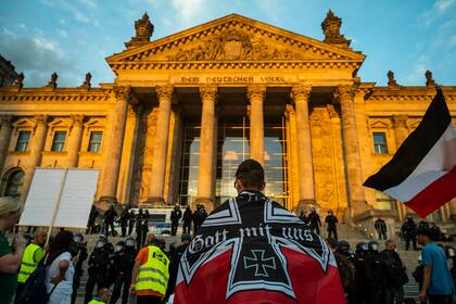 Un manifestante envuelto en una bandera del imperio alemán se enfrenta a policías antidisturbios haciendo guardia frente al edificio del Reichstag, en Berlín, el 29 de agosto de 2020