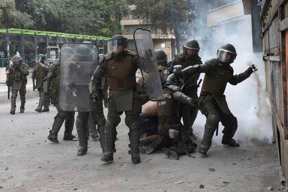 Un manifestante es detenido mientras un policía antidisturbios se prepara para lanzar gas lacrimógeno durante una protesta contra el gobierno en Santiago, Chile, el 21 de noviembre de 2019