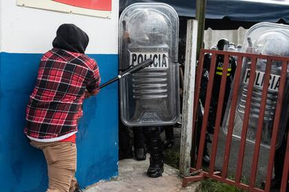 Un manifestante golpea el escudo de la policía antidisturbios con un bate de béisbol durante una protesta contra la moción del gobierno de aumentar los impuestos a fin de llegar a un acuerdo crediticio con el FMI, frente a la casa presidencial en San José, el 12 de octubre de 2020