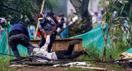 Un manifestante herido es tirado por otros hombres durante enfrentamientos con la policía antidisturbios luego de una protesta contra el proyecto de ley de reforma tributaria presentado por el presidente colombiano Iván Duque, en Cali, Colombia