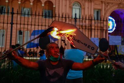 Un manifestante incendia un cartel frente a la Casa Rosada durante la manifestación por el 27F