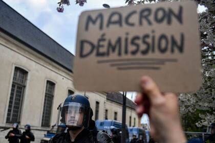 Un manifestante levanta una pancarta en la que se lee "Macron, dimisión".