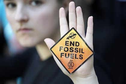 Un manifestante muestra un cartel que dice "acabar con los combustibles fósiles" en la Cumbre Climática de la ONU COP28, el sábado 2 de diciembre de 2023, en Dubái, Emiratos Árabes Unidos.