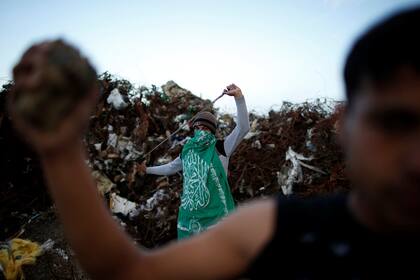 Un manifestante palestino, apodado Abu Akram, que lleva una bandera de Hamas, sostiene una honda en la escena de los enfrentamientos con las tropas israelíes cerca de la frontera con Israel, al este de la ciudad de Gaza