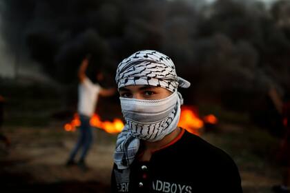 Un manifestante palestino, que se identificó a sí mismo como Ahmed frente a la quema de neumáticos en la escena de los enfrentamientos con las tropas israelíes cerca de la frontera con Israel, al este de la ciudad de Gaza