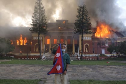 Un manifestante posa frente al palacio presidencial en Katmandú mientras el edificio arde durante las protestas del 9 de septiembre de 2025