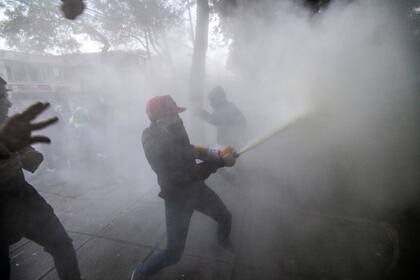 Un manifestante rocía un extintor durante una protesta por la muerte de un abogado bajo custodia policial, en Bogotá el 9 de septiembre de 2020