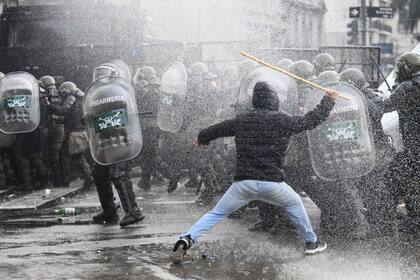 Un manifestante se enfrenta a la policía antidisturbios, que le arroja agua frente al Congreso Nacional