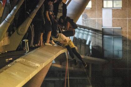 Un manifestante se prepara para bajar una cuerda desde un puente a una carretera, para escapar del campus de la Universidad Politécnica de Hong Kong y de la policía, en el distrito de Hung Hom el 18 de noviembre de 2019