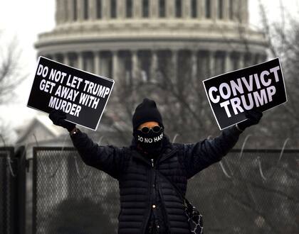 Un manifestante sostiene carteles cerca de Union Station durante el quinto día del segundo juicio político del presidente de Estados Unidos, Trump, en el Senado