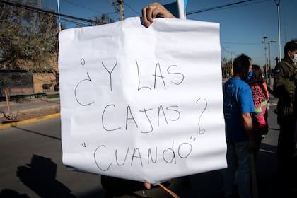 Un manifestante sostiene un cartel pidiendo cajas de ayuda durante una protesta contra el gobierno del presidente chileno Sebastián Piñera en medio de la pandemia de coronavirus, en Santiago, el 25 de mayo de 2020
