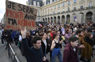 Un manifestante sostiene una pancarta en la que se lee "Estaré muerto antes de jubilarme" durante una manifestación un día después de que el gobierno francés impulsara una reforma de las pensiones a través del parlamento sin votación, utilizando el artículo 49.3 de la Constitución, en Rennes, oeste de Francia, el 17 de marzo de 2023.