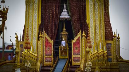 La urna funeraria del fallecido rey tailandés Bhumibol Adulyadej es transportada por una rampa al crematorio mientras los oficiales observan