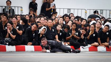 Un oficial de policía y deudos reaccionan cuando el rey de Tailandia, Maha Vajiralongkorn, pasa durante la procesión de cremación real del fallecido rey Bhumibol Adulyadej en el Gran Palacio de Bangkok