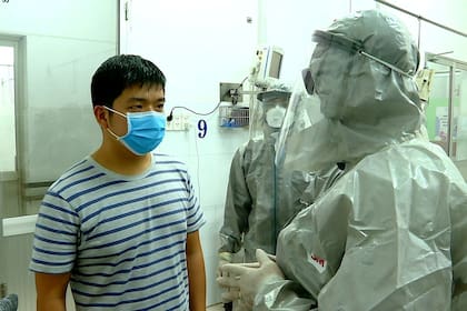 Un médico habla con un paciente contagiado con coronavirus en Vietnam, uno de los dos casos identificados en ese país