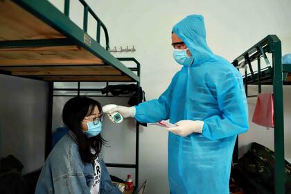 Un médico verificao la temperatura de una mujer en una instalación de cuarentena, en la provincia de Vinh Phuc, en el norte de Vietnam