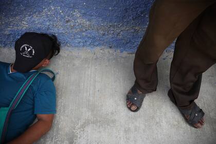 Un miembro de "El Machete" duerme una siesta en la acera mientras espera afuera durante una reunión entre autoridades locales y líderes del grupo de autodefensas en Pantelho, estado de Chiapas