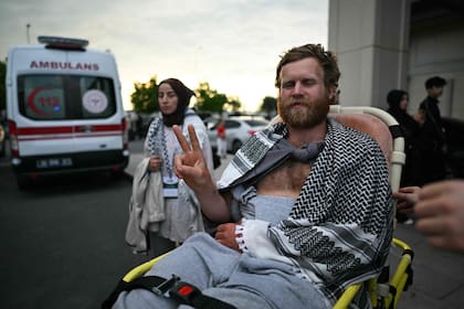 Un miembro de la Flotilla Global Sumud, que se dirigía a Gaza y fue arrestado y deportado por Israel, es sacado de una terminal en silla de ruedas tras la llegada del grupo al aeropuerto de Estambul el 21 de mayo de 2026 ( Ozan Kose / AFP)