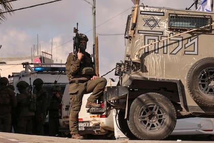 Un miembro de las fuerzas de seguridad israelíes está en guardia cuando otros revisan un automóvil que, según los informes, un palestino utiliza un ataque de embrujos frustrado contra tropas colocadas cerca del asentamiento de Kiryat Arba en las afueras de la ciudad ocupada de Hebrón, Cisjordania, en Febrero en febrero 1, 2024,