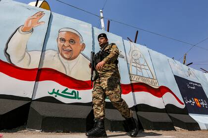 Un miembro de las fuerzas iraquíes pasa junto a un mural que representa al Papa Francisco en un muro afuera de la Iglesia católica siríaca de Nuestra Señora de la Liberación en el distrito de Karrada de la capital de Irak, Bagdad