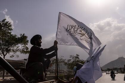 Un miembro de los talibanes cuelga una bandera de la milicia extremista en la antena de su vehículo