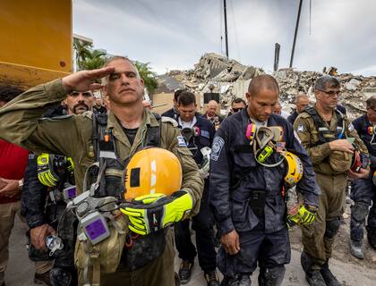 Un miembro del equipo israelí de búsqueda y rescate saluda frente a los escombros del edificio residencial Champlain Towers South