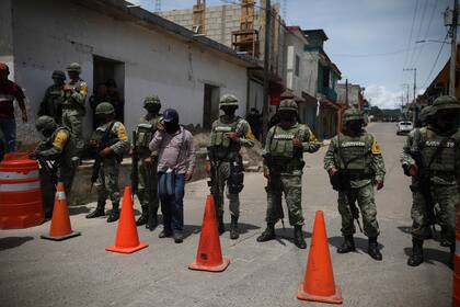 Un miembro del grupo "El Machete" camina a través de un cordón de soldados del Ejército Mexicano que resguardan el perímetro durante una reunión entre autoridades locales y líderes del grupo, en Chiapas