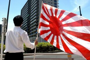 Un miembro del grupo ultraderechista japonés sostiene una bandera del Sol Naciente frente al edificio donde se aloja el equipo olímpico de Corea del Sur en la Villa Olímpicos de Tokio, Japón, el 16 de julio de 2021