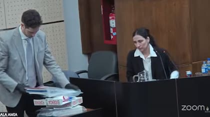 Un miembro del tribunal le exhibe los cuadernos a la periodista.